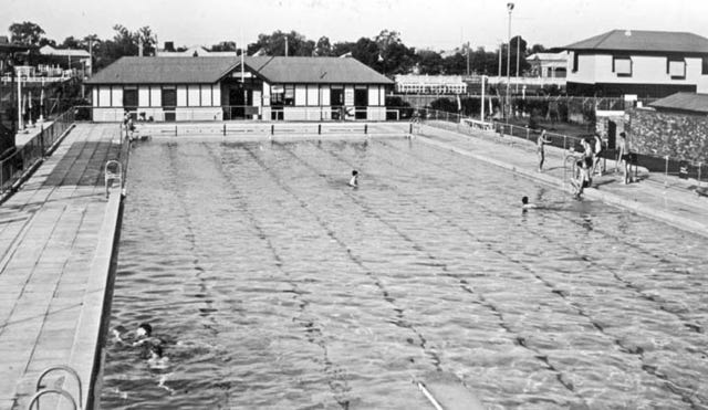 Black and white photo of a swimming pool from the 1940s with a few (white) Australians swimming in it