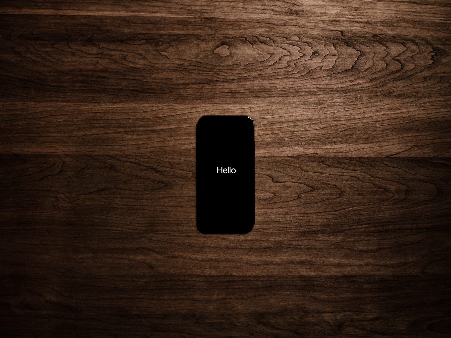 Phone on wood background with hello displayed on the screen