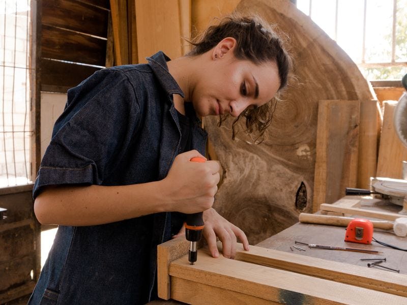 White person with brown hair using a tool to build something out of wood