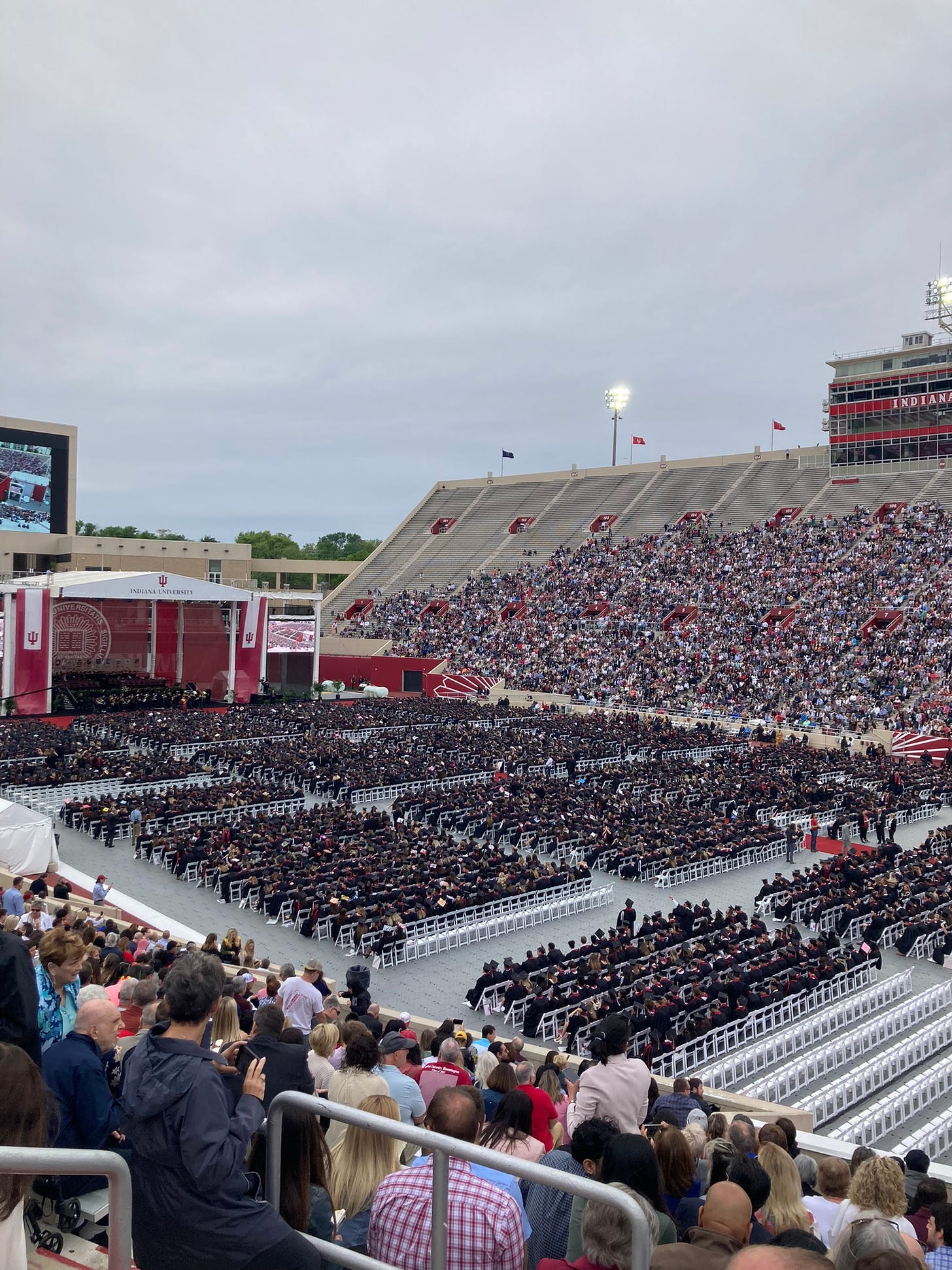 Memorial stadium, the field filled with undergraduates in black robes the stands filled with family and friends, under a gray sky