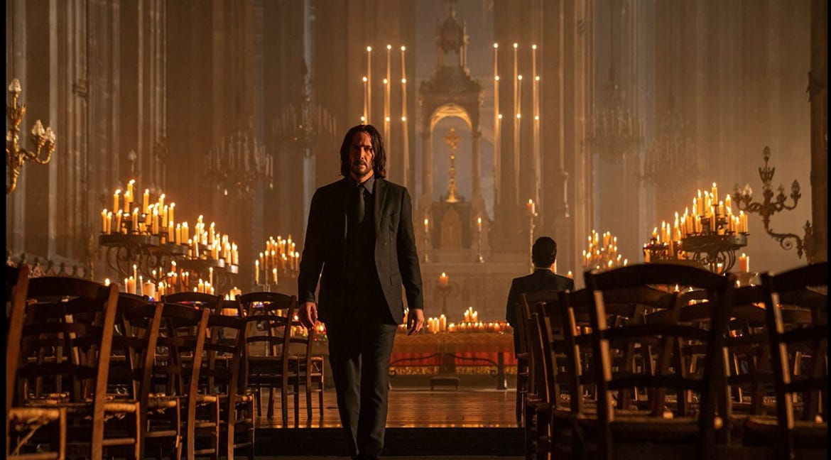 John Wick 4 - Keanu Reeves andando para fora de uma catedral repleta de velas, em tons quentes e iluminada. Ao lado direito da foto é possível encontrar o Caine sentado, contemplando o altar