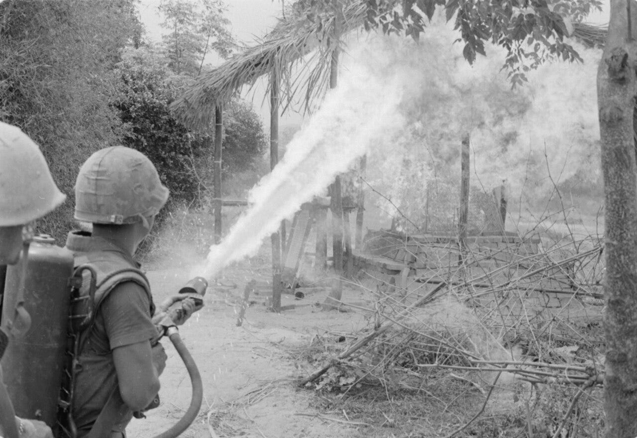 US GIs wield a flamethrower in a Vietnamese village