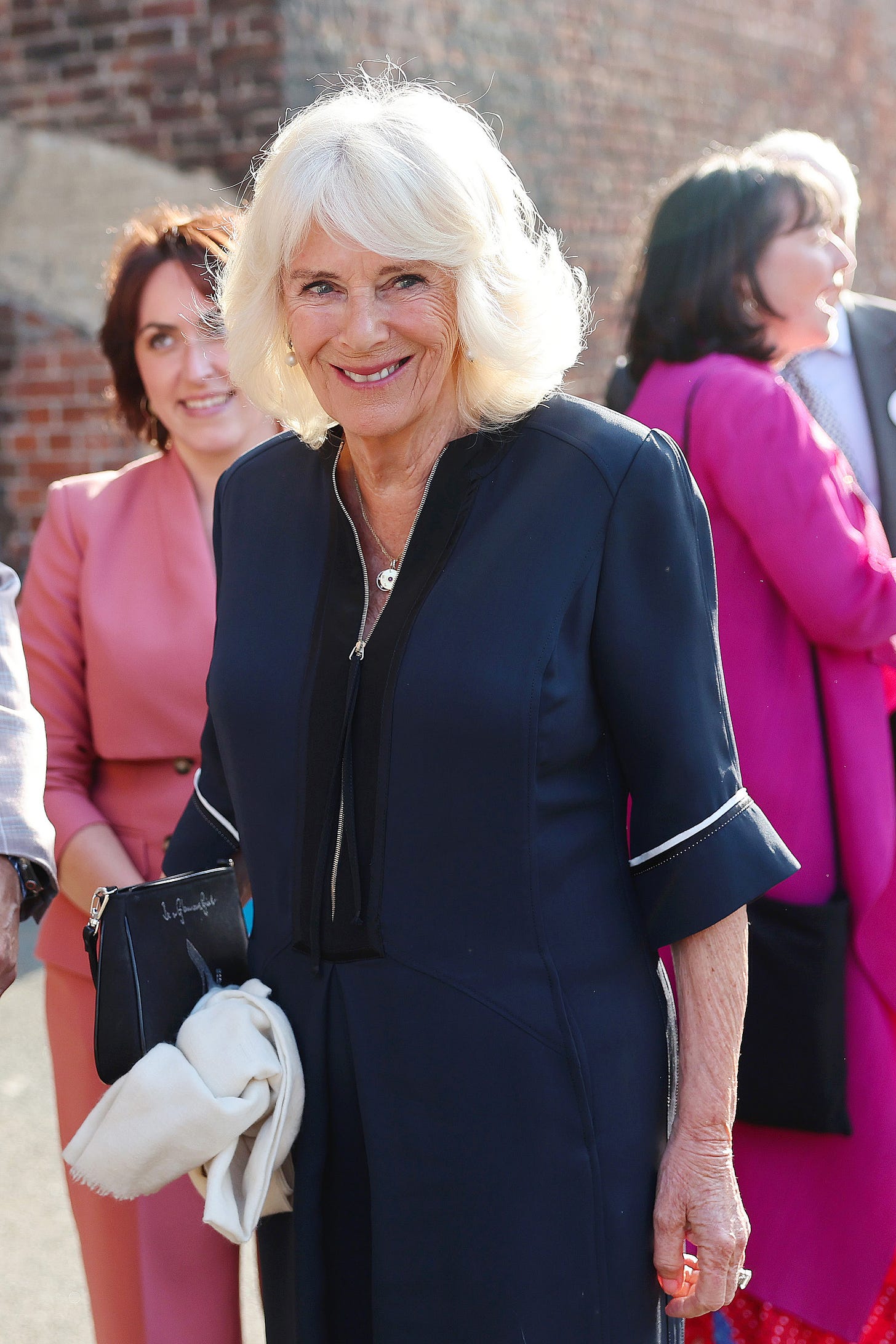 Queen Camilla wearing navy outfit and slogan bag