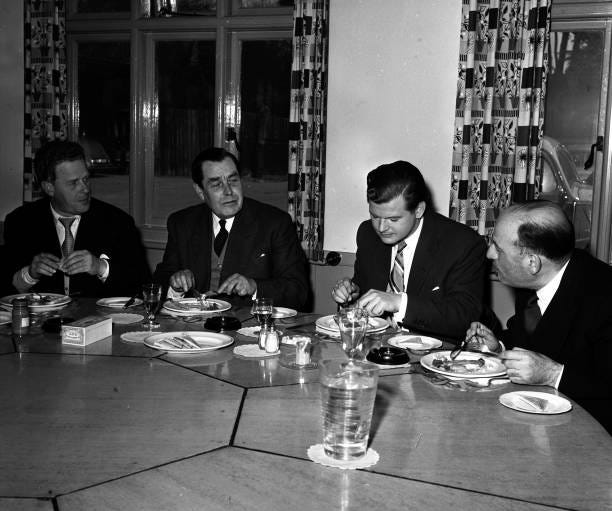 London, England British actor and comedian Benny Hill is pictured eating lunch with L-R: Basil Dearden , TEB Clarke , Hill, and Sir Michael Balcon ,...
