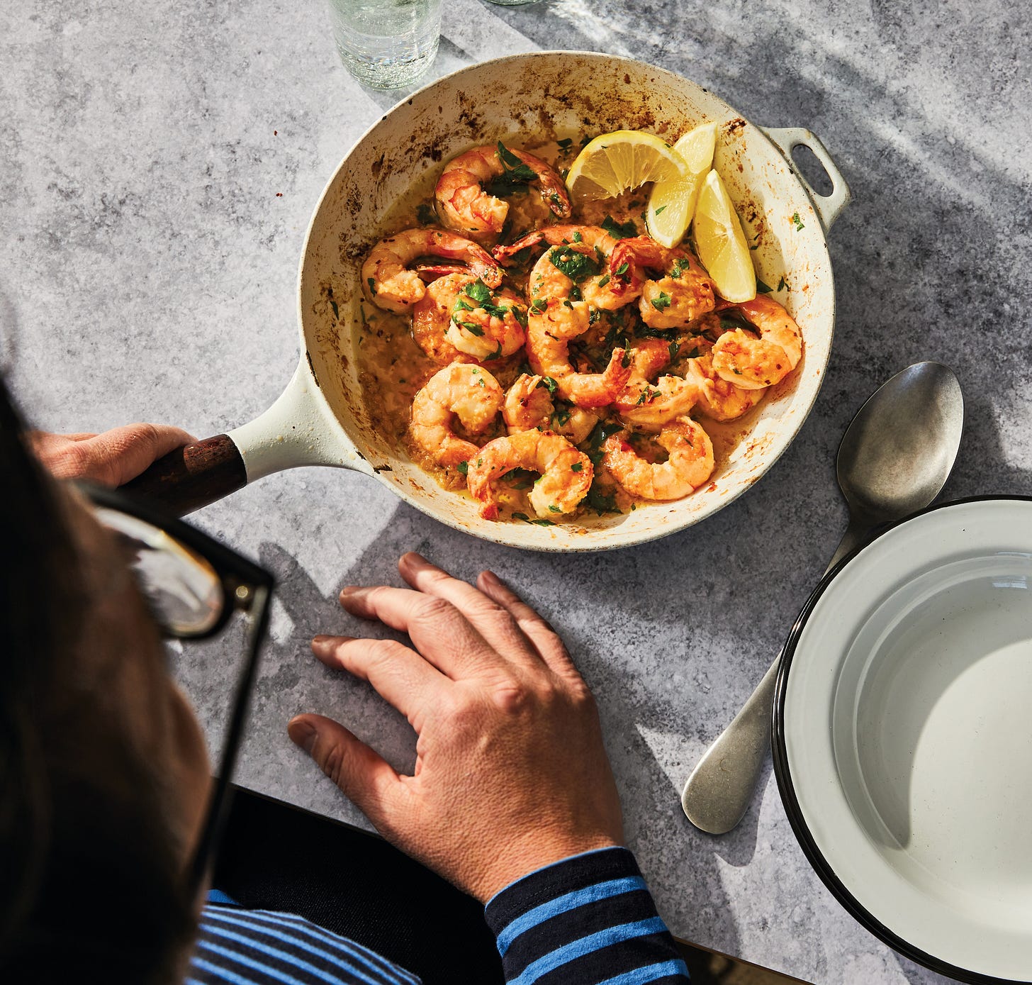 Lemony shrimp in a white skillet on a gray counter.