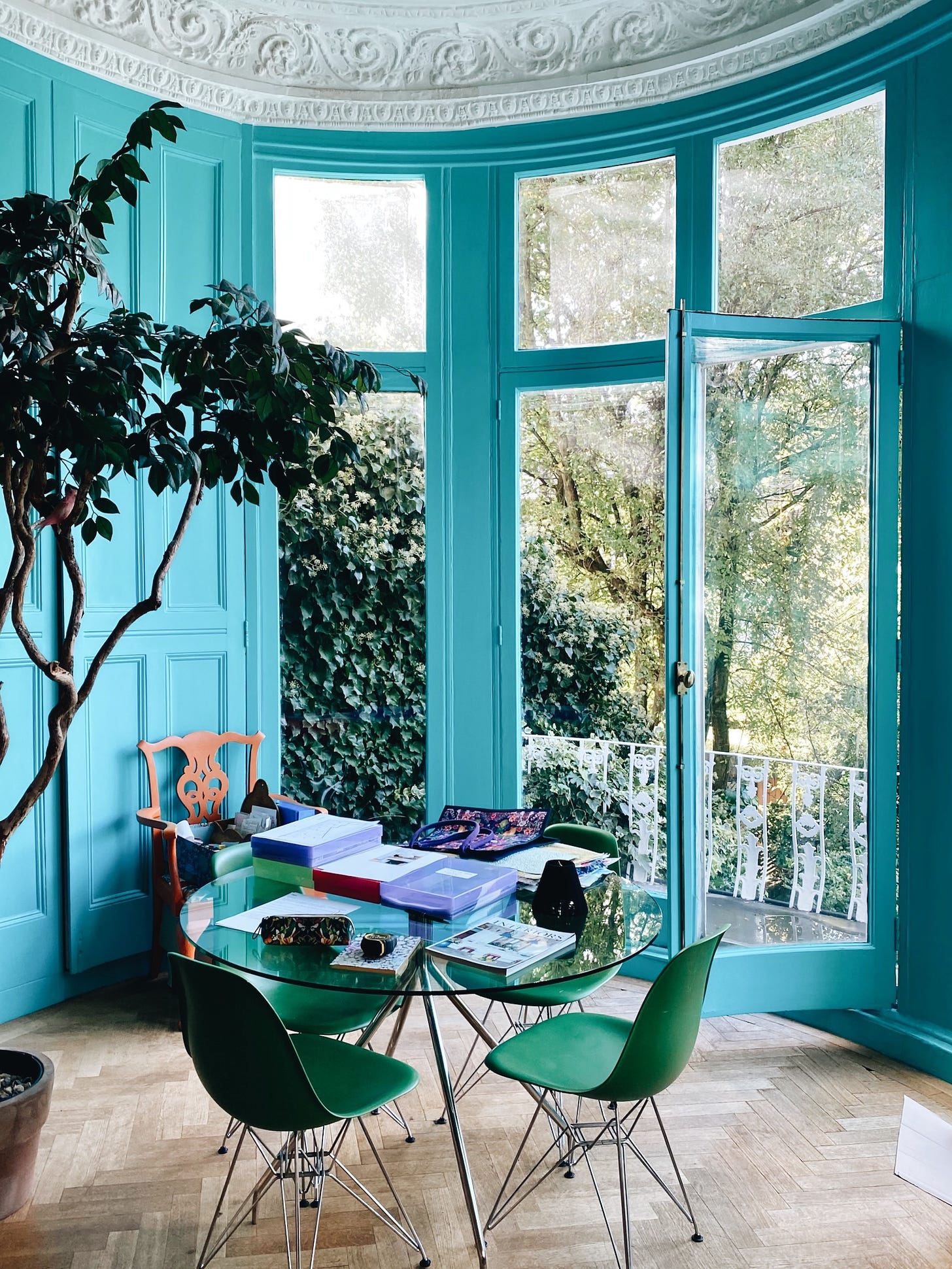 Matthew Williamson London home turquoise curved bay windows, round glass table and green dining chairs