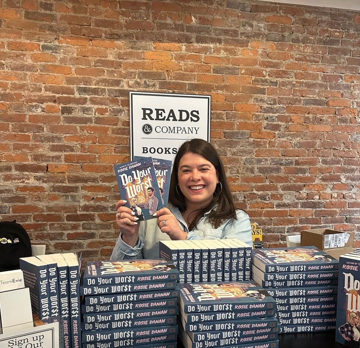 A person smiling at a table with books

Description automatically generated