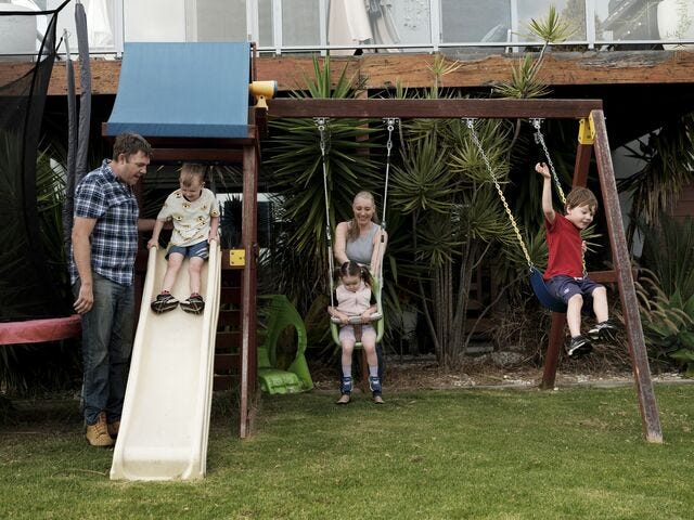 Jen Spears and husband Scott play with her children in the front yard at their home in Tura Beach, Friday 15th March, 2023.