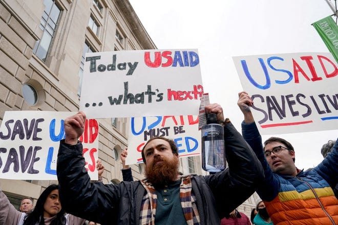 FILE PHOTO: People hold placards outside the USAID building, after billionaire Elon Musk, who is heading U.S. President Donald Trump's drive to shrink the federal government, said work is underway to shut down the U.S. foreign aid agency USAID, in Washington, U.S., February 3, 2025. REUTERS/Kent Nishimura//File Photo