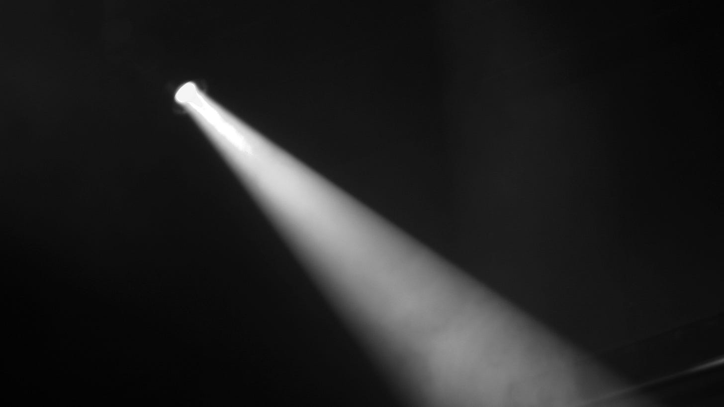 A spotlight shines diagonally down in a dark room