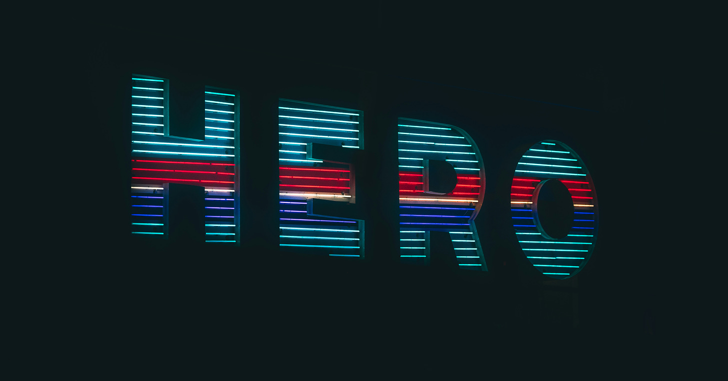 The word HERO (in all caps) is displayed in light blue, dark blue, and red, over a black background.
