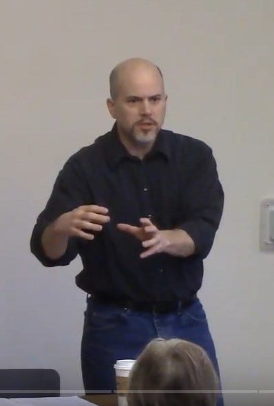 man standing in front of people talking with his hands