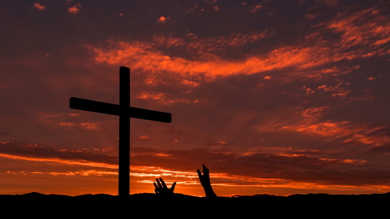 A person lifting their hands toward the cross. 