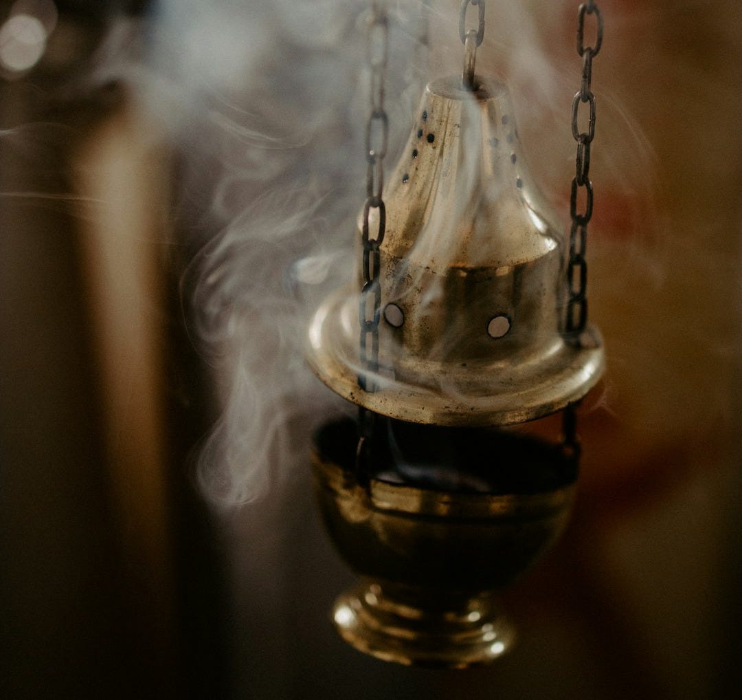 a small bell hanging from a chain with smoke coming out of it