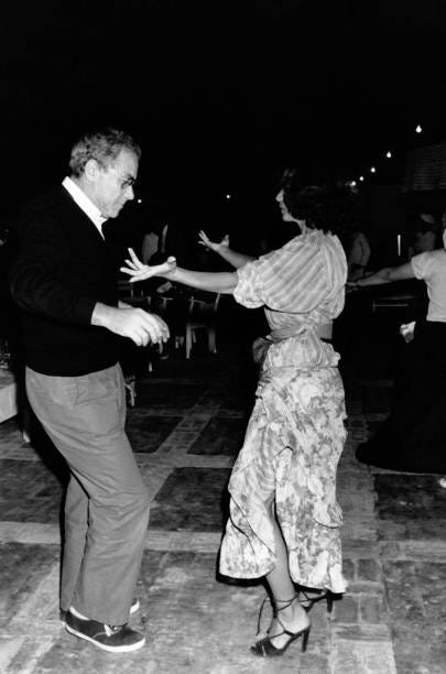 Le producteur de films Gérard Lebovici dansant avec une jeune femme lors du tournage du film 'Les Morfalous' d'Henri Verneuil, en mars 1984.