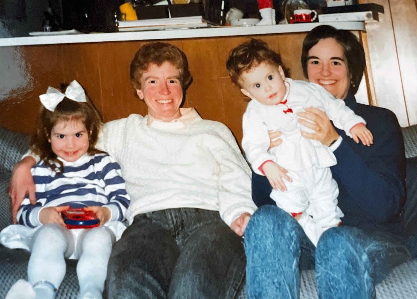 Two children and two adult women sitting on a sofa together