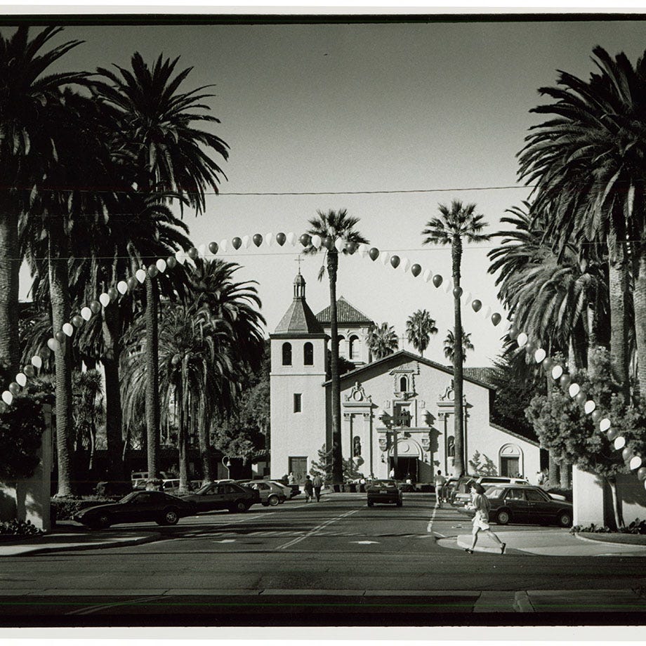 Palm palm trees leading to the Mission Church with a balloon banner