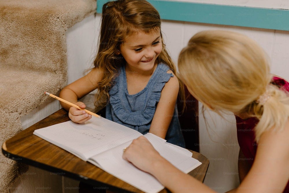 a little girl sitting at a desk writing on a piece of paper