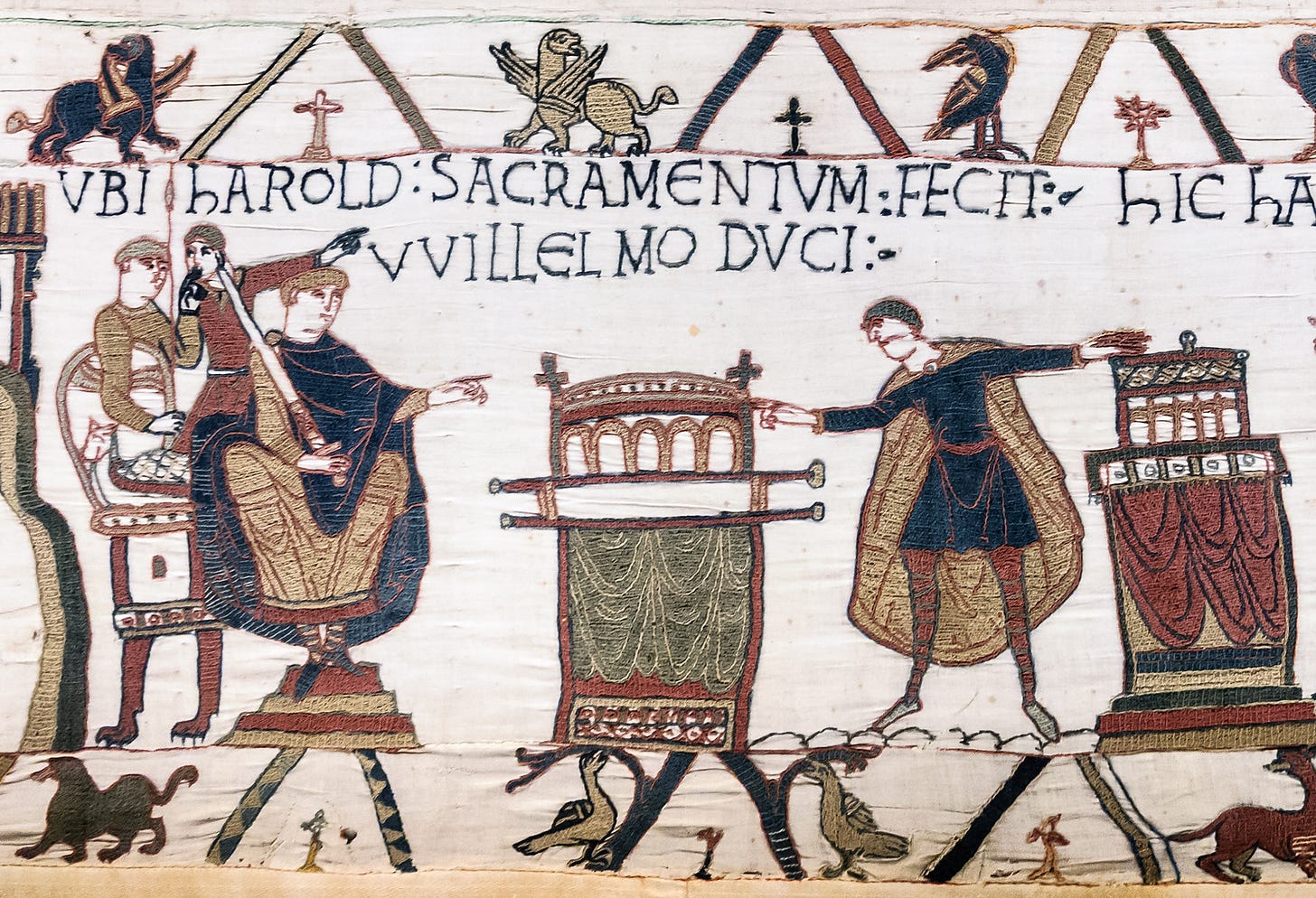 Scene from the Bayeux Tapestry of two men pointing at each other with onlookers in the background; there's Latin text embriodered above them describing Harold's oath.