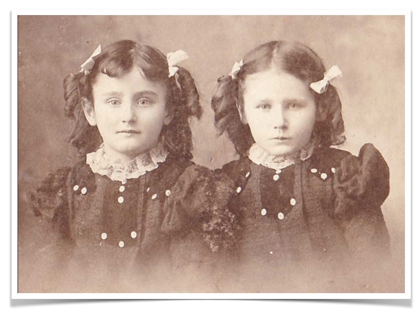 Sepia toned image of two young girls dressed similarly.