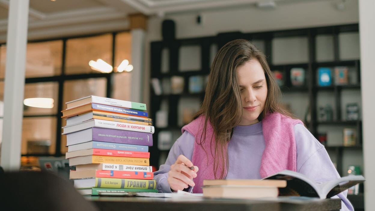 Student at desk with pile of books