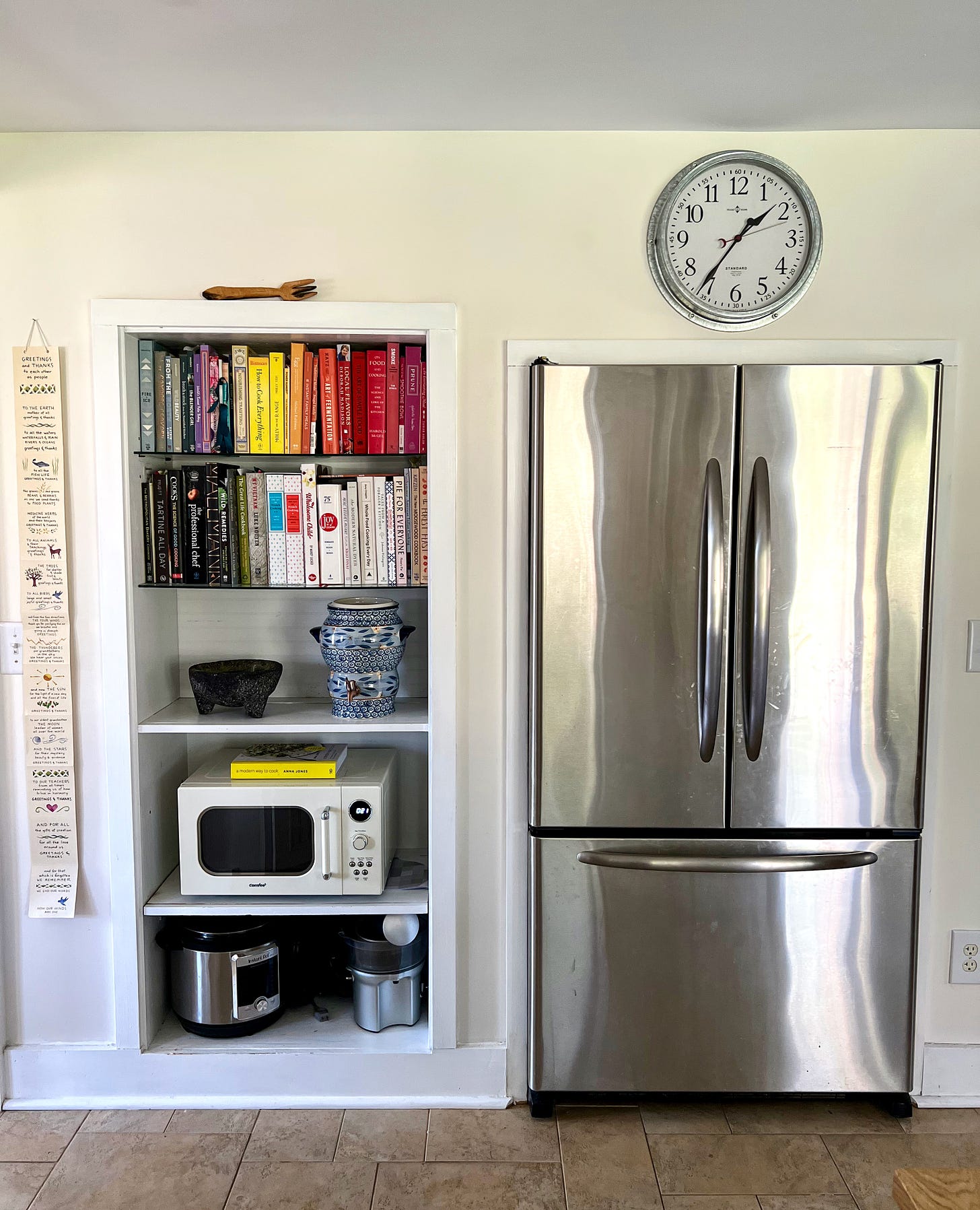 Large fridge with shelves of books on the side. 