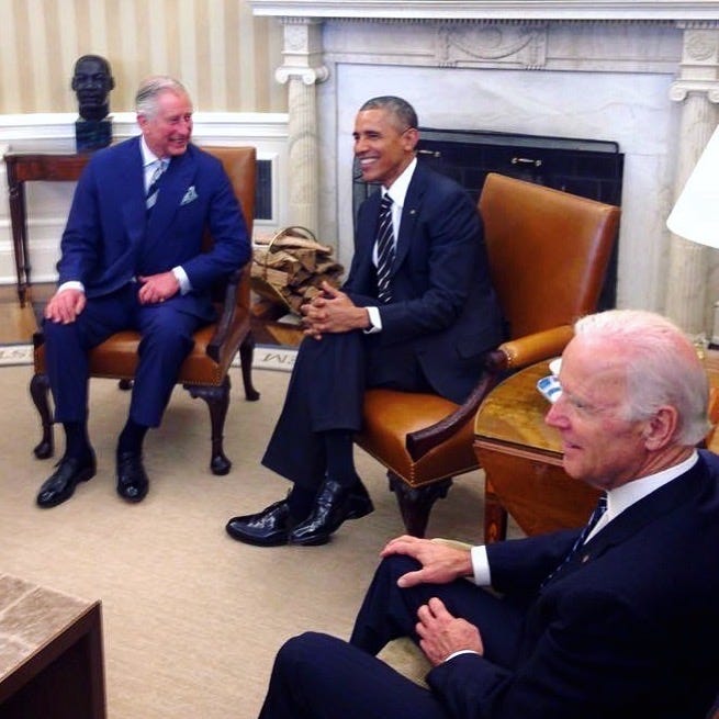 The then Prince Charles, Barack Obama and Joe Biden sitting on armchairs in the Oval Office and laughing