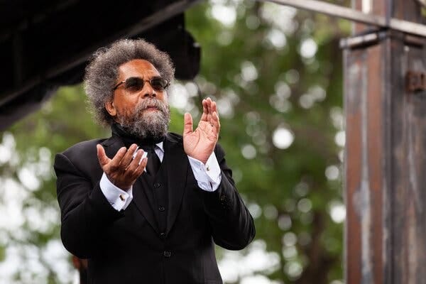 Cornel West, wearing a black suit jacket and sunglasses, claps his hands while at an event in Washington last year.