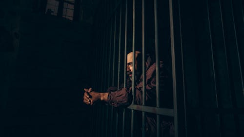 Free A Prisoner Standing behind the Bars  Stock Photo