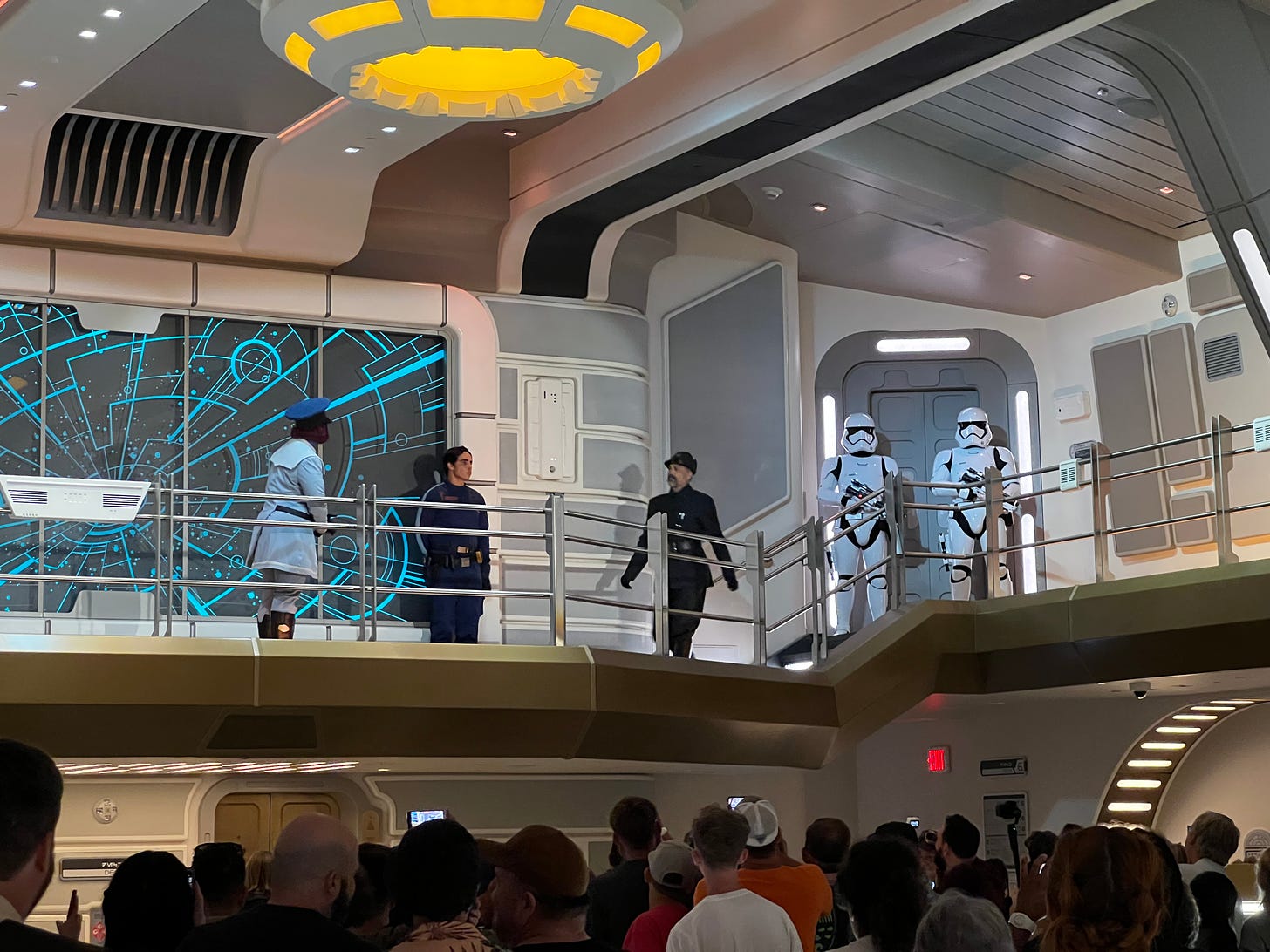 A First Order officer on the atrium walkway, with two stormtroopers behind him