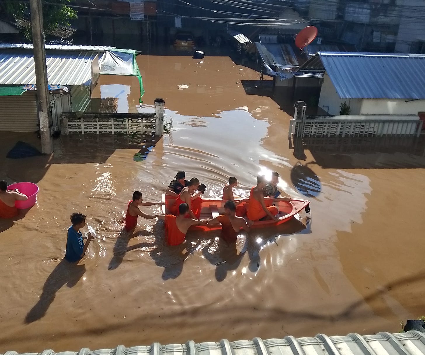 Young novice monks and neighbors bring a small boat through flooded streets, Chiang Mai, Thailand