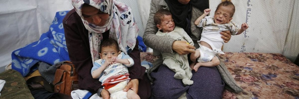 women hold three malnourished Gaza triplets
