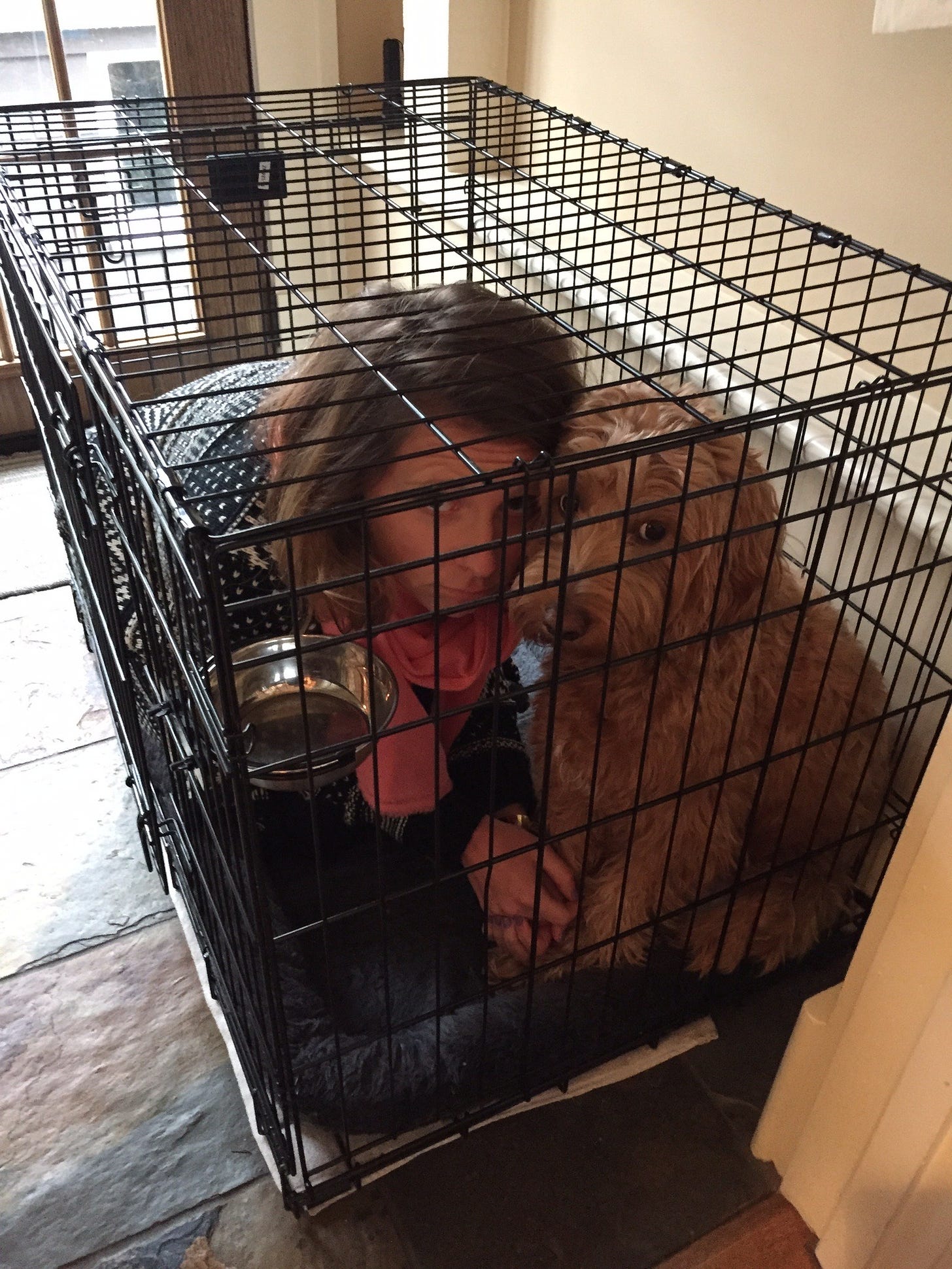 Woman in a dog crate with a dog.