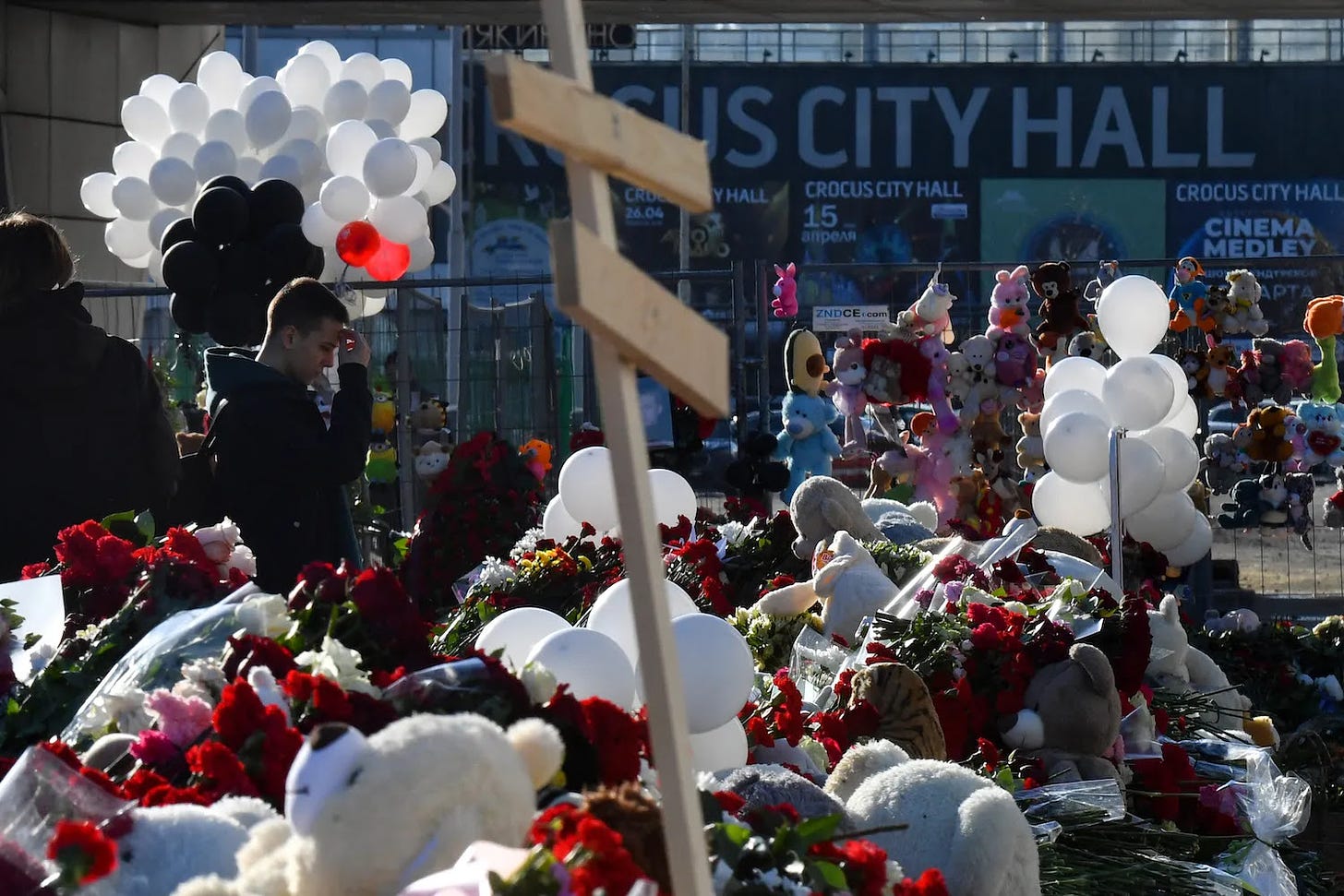 People bring flowers to a makeshift memorial in front of Russia’s Crocus City Hall.