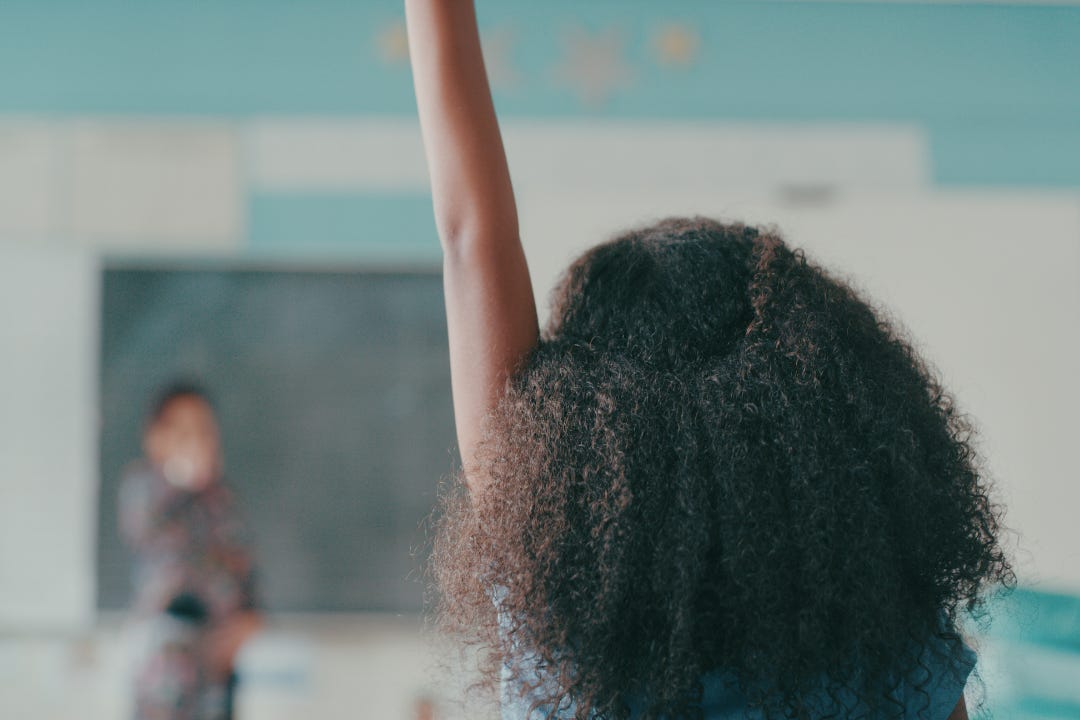 Shot of a young Black girl child raising her hand in a classroom