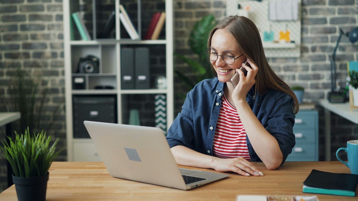 woman with phone sitting at laptop woman with phone sitting at laptop