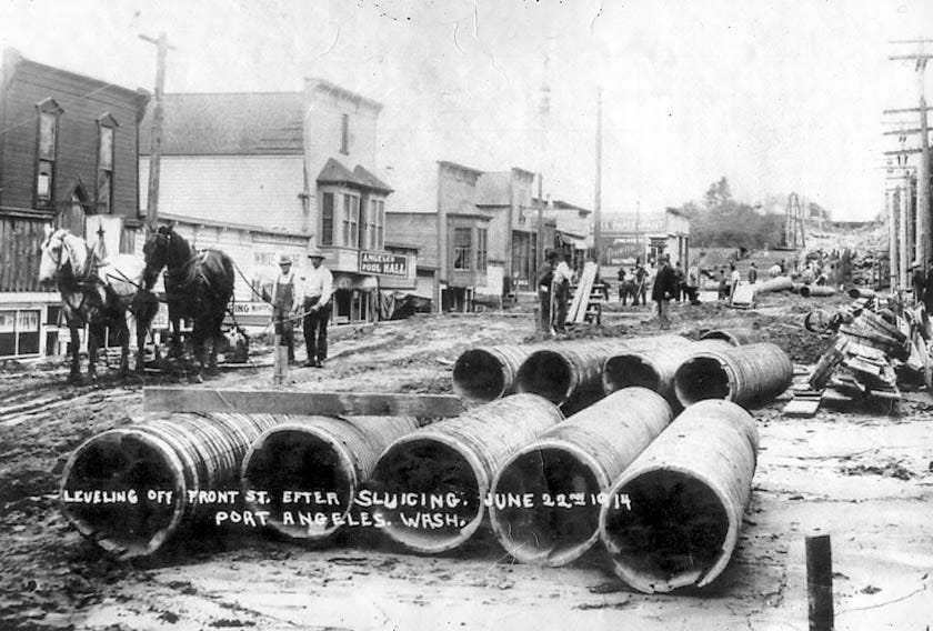 Teams of horses draw equipment through the mud of the just-completed raising of Front Street in a June 22