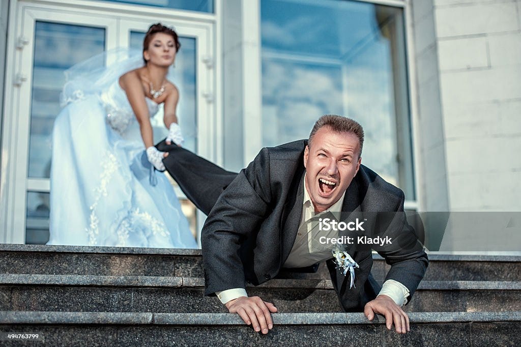 Bride dragging groom at the wedding. Bride leg pulls groom at the wedding. Wedding Stock Photo