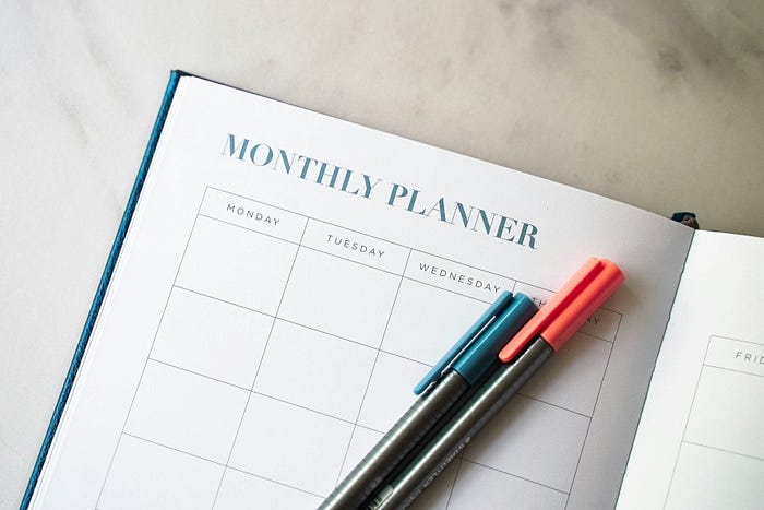 Imagem de planner mensal em branco com canetas em cima