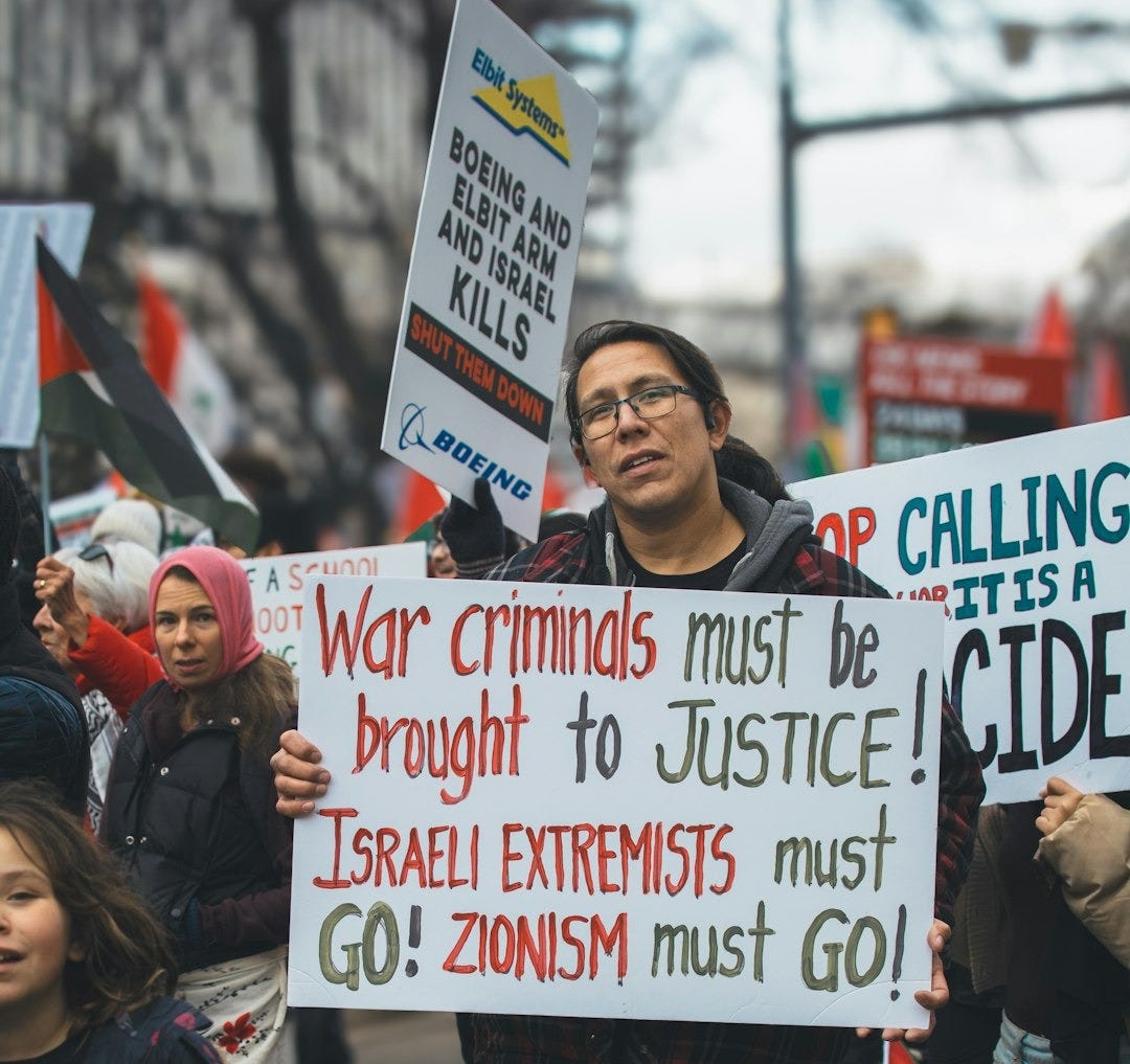 a man holding a sign in front of a crowd of people a man holding a sign in front of a crowd of people