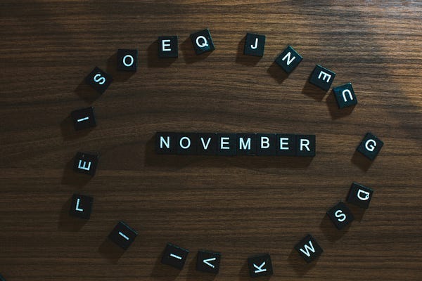 The word, “NOVEMBER” on a wooden tabloe surrounded by alphabets. The word, “NOVEMBER” on a wooden tabloe surrounded by alphabets.