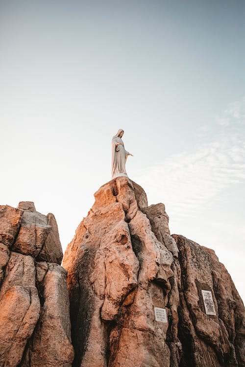 Free Statue of St. Mary Standing on Top of Rock Stock Photo