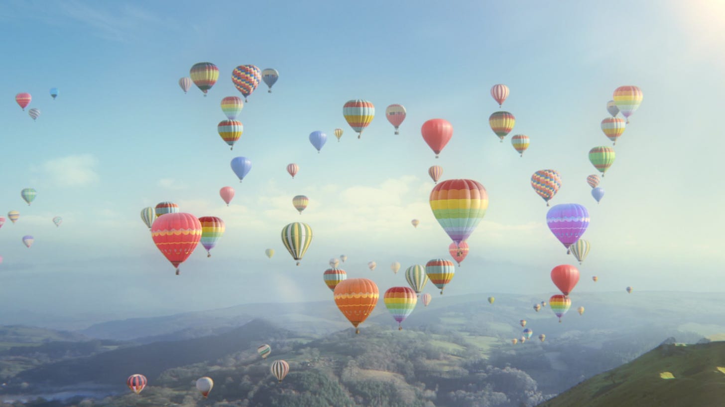 Several groups of very colorful hot air balloons spelling out "joy" over a mountain terrain.  It's light and airy and breathtaking.