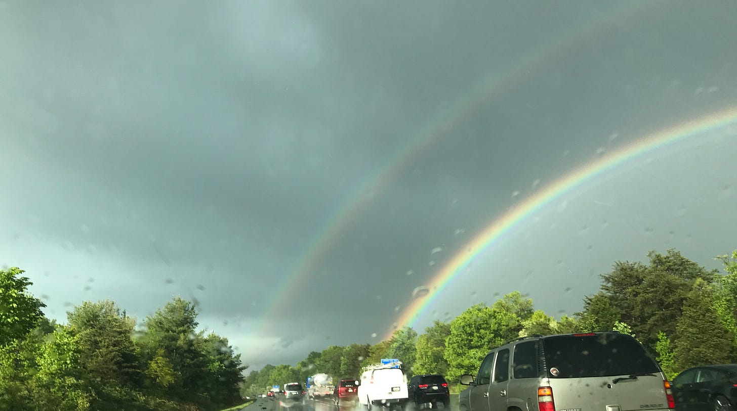 Rainy highway, view of double rainbow through windshield of car