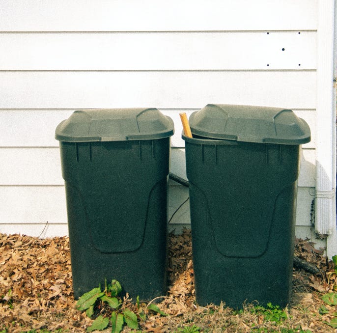 two green plastic trash barrels