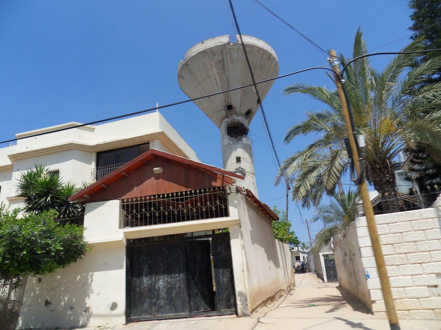 An empty concrete water tower with a large hole from a missile near its base