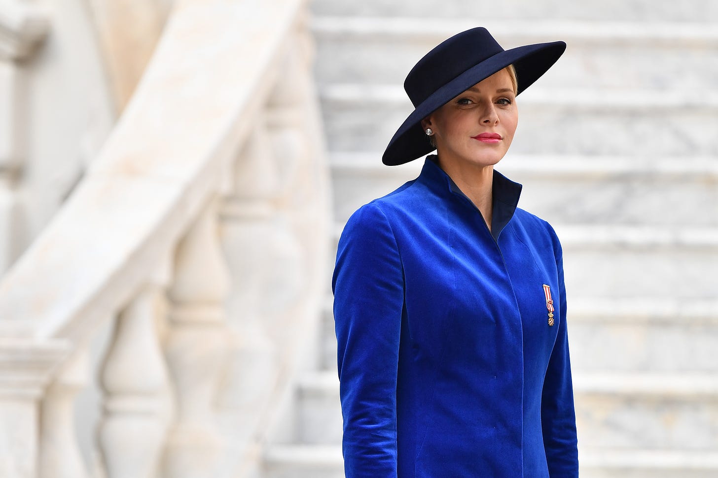 Princess Charlene wearing a blue coat and asymmetric black hat