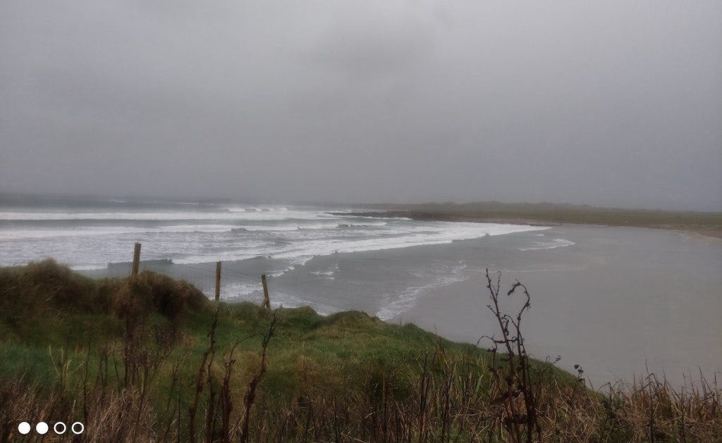 A coastal view of low waves crashing in to a small bay, just a few hundred metres down the road