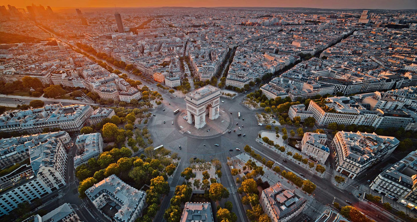 A triumphal arch lies at the center of Paris, France.