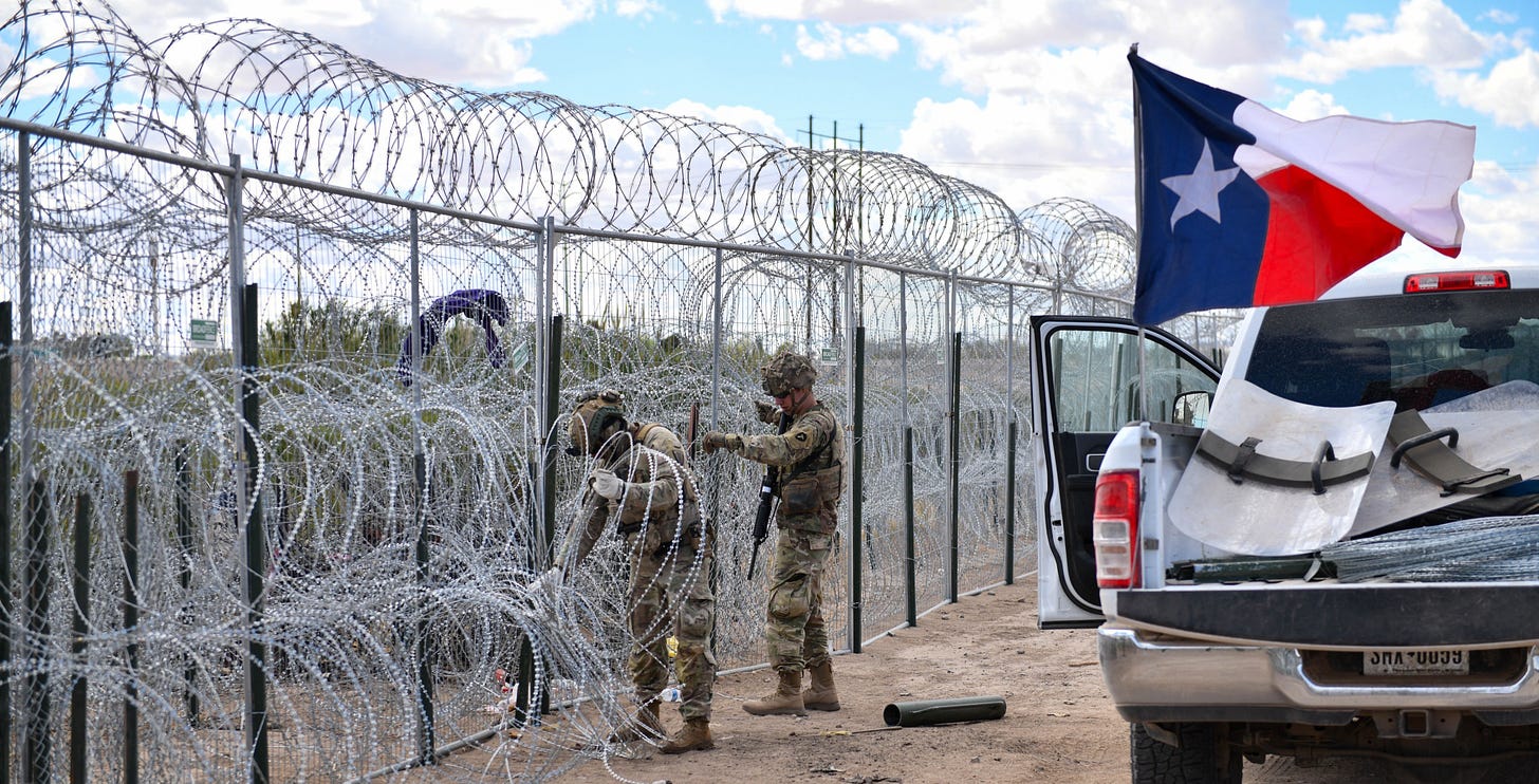 Texas National Guard troops build barbed wire barrier along the Rio Grande